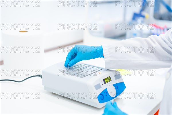 Close-up photo of the hands of a biologist using a machine to work on cancer cells