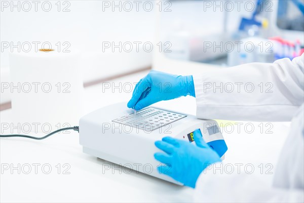 Hands of a biologist with protective blue latex gloves working on a machine to analyse cells