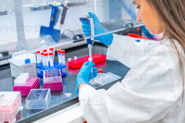 Rear view close-up of a female biologist pip petting cells in a laboratory