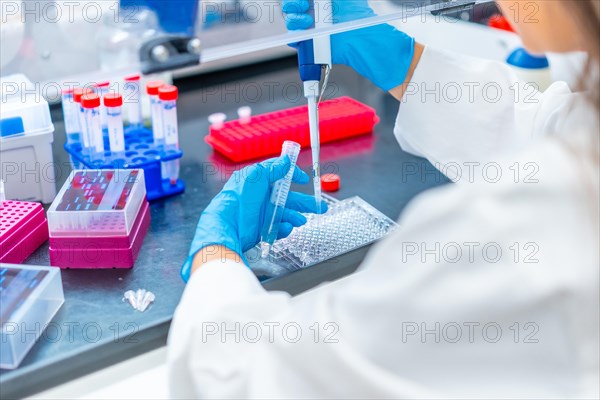 Doctor extracting samples with a pipette from a tray in a cancer research laboratory