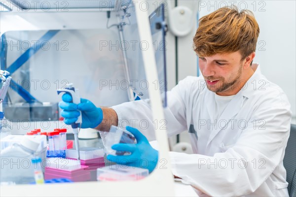 Side view of a young and happy scientist pipetting medical samples into microplate in laboratory