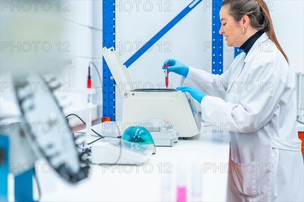 Side view of a smiling scientist placing a blood sample in a centrifuge in a research laboratory