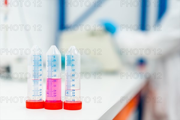 Three tubes with samples in the table of a laboratory with someone working on the background