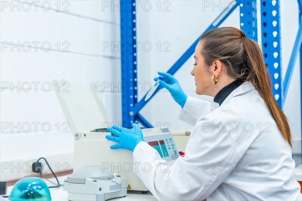 Female biologist extracting blood samples from a centrifuge machine sitting on a laboratory table