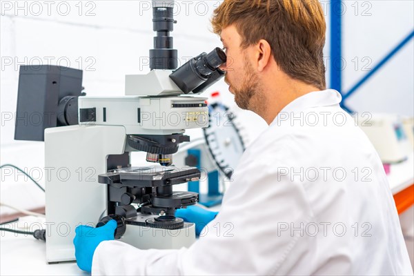 Rear view of a young scientist analyzing cells using a microscope in a research laboratory