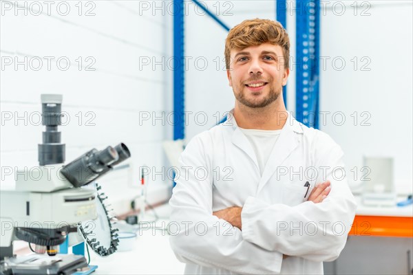 Portrait of a young biologist standing with arms crossed in a laboratory