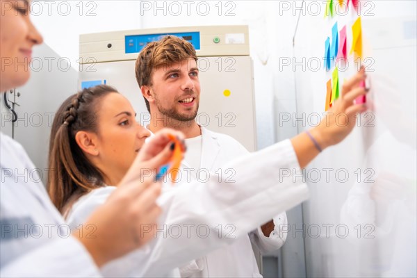 Side view of a group of creative process using adhesives notes in a cancer research laboratory