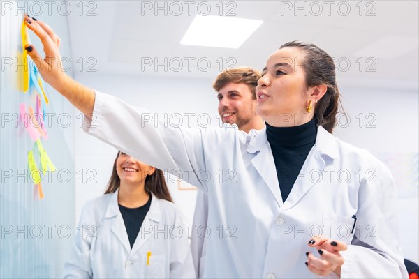 Three young biologists during a brainstorming meeting in a cancer research laboratory