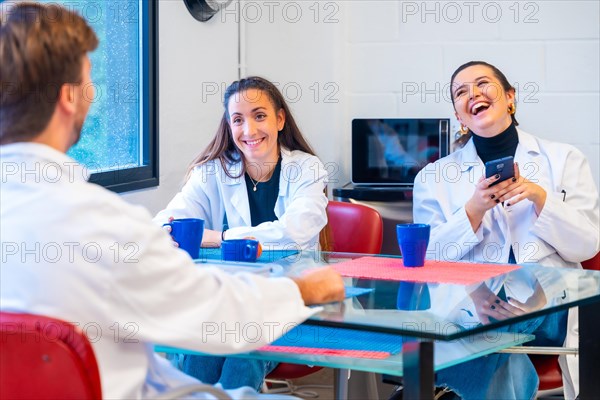 Group of three young scientists sitting and chatting during a coffee break