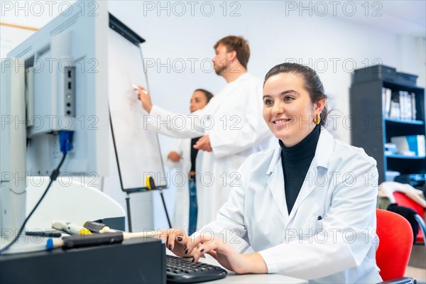 Smiling young scientist using computer in the office of a laboratory