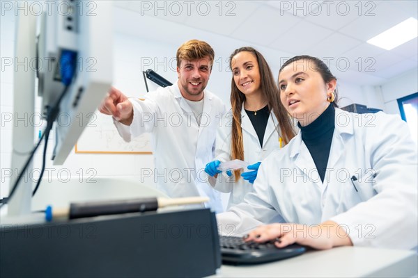 Happy doctors using computer and pointing to the screen in a research laboratory