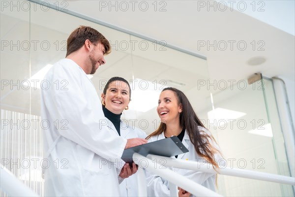 Low angle view of three young scientists talking and reading documents in a laboratory