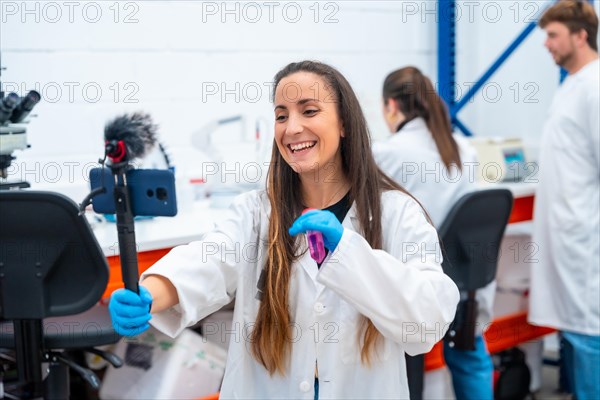 Young happy scientist of a research laboratory broadcasting using a mobile