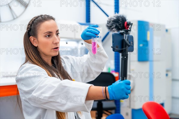 Scientist showing samples while recording a video with mobile standing on a laboratory