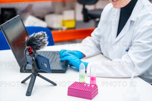 Scientists using mobile to recording while talking next to samples and using laptop in a research laboratory