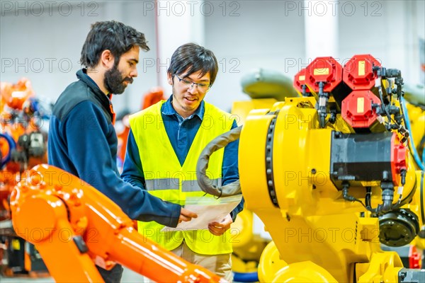 International team of engineers reading an inform in a industry of robotic arms