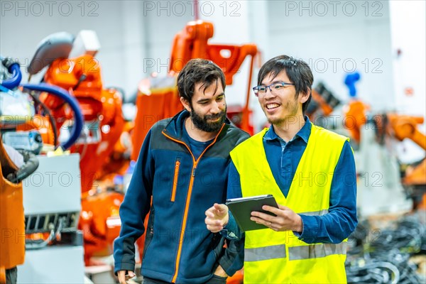 Multicultural team of engineers controlling the production of robotic arms in the assembly line