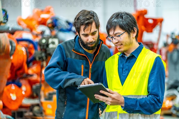 Engineers talking while reading reports in a futuristic industry of robotic arms