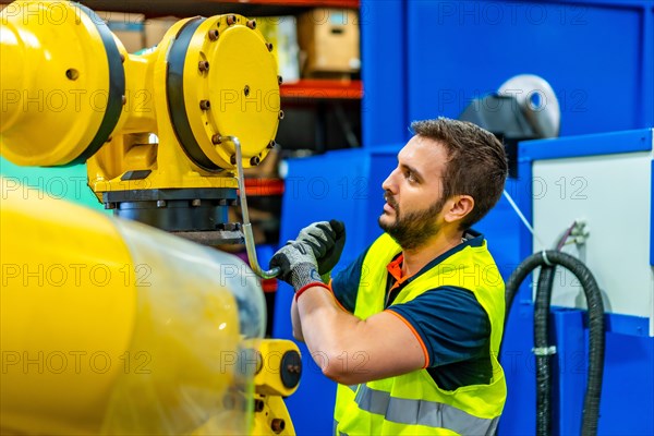 Mechanic repairing a piece of a robotic arm in an assembly line