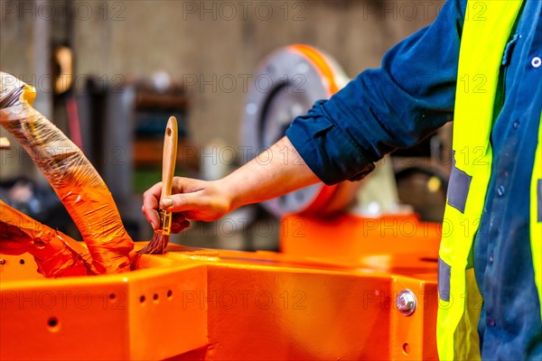 Cropped photo of a worker painting a part of a robotic arm