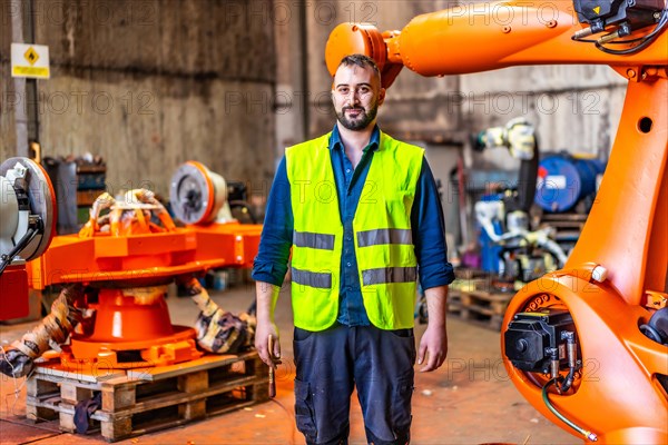 Portrait of a mechanic in uniform in an industry that build robotic arms