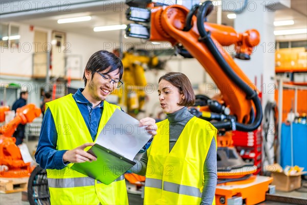 Male and female multi-ethnic engineers reading data while working in a robotic industry