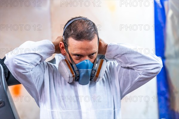 Close-up photo of an industrial painter putting on protective gear for work