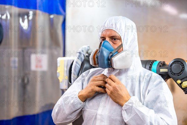 Industrial painter dressing with white safety uniform and gear to work