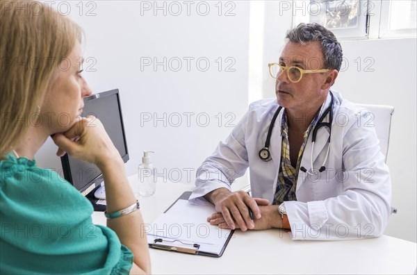 Male doctor telling his patient her diagnostic in his medical office