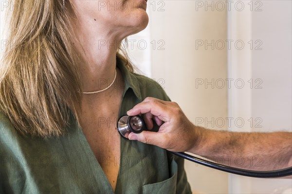 Close-up of a doctor checking her patient's heart beat with stethoscope