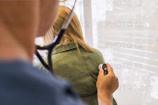 Doctor using stethoscope on his patient's back to listening to lungs for breathing problem. Copy space