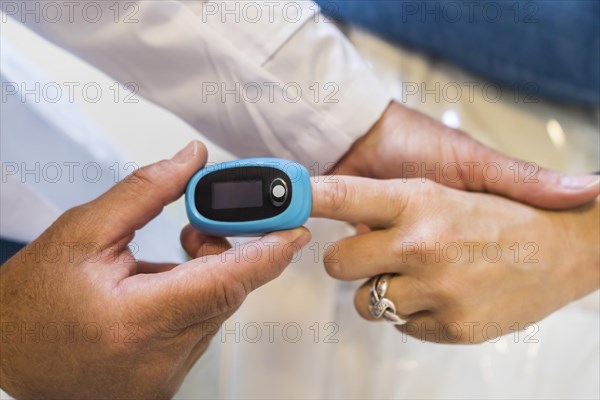 Doctor is putting a pulse oximeter in his patient's hand for measuring oxygen saturation in blood and heart rate