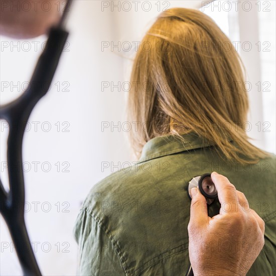 Doctor using stethoscope on his patient's back to listening to lungs for breathing problem
