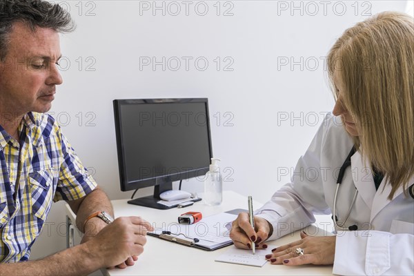 Female doctor writing prescription to her patient