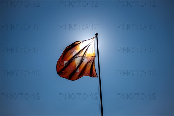 Beautiful Swiss Flag Against Blue Clear Sky and the Sun in a Windy Day in Switzerland