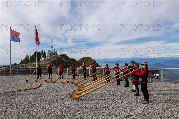 Group of Musicians Playing on Horns of the Alps with Mountainscape and View over Snow Capped Monte Rosa in a Sunny Day in Monte Generoso