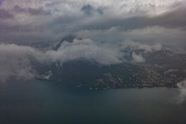 Aerial View over City and Lake Lugano in Valley with Mountainscape with Storm Clouds in Lugano