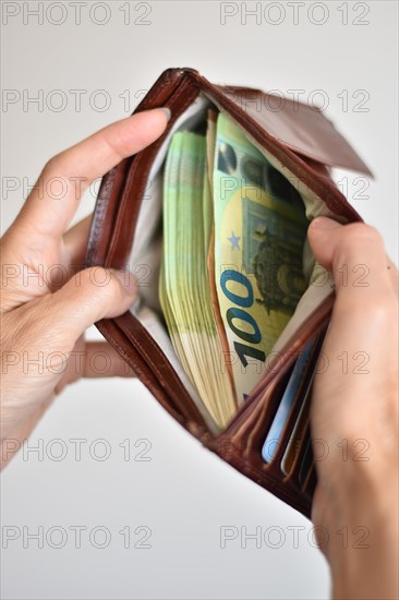 Hands holding many euro banknotes in a leather wallet