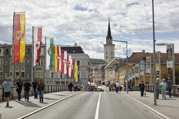 Flags on the Drau bridge with parish church