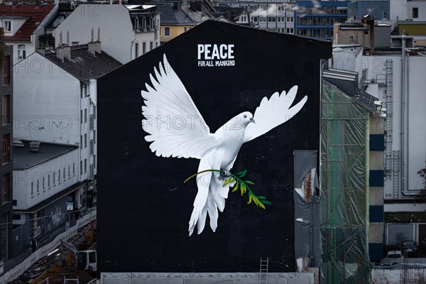 PEACE FOR ALL MANKIND is written above the image of a giant dove of peace on the wall of a house in Frankfurt am Main: a message of peace in the contemporary historical context of the escalated Middle East conflict and the ongoing war of aggression in Ukraine