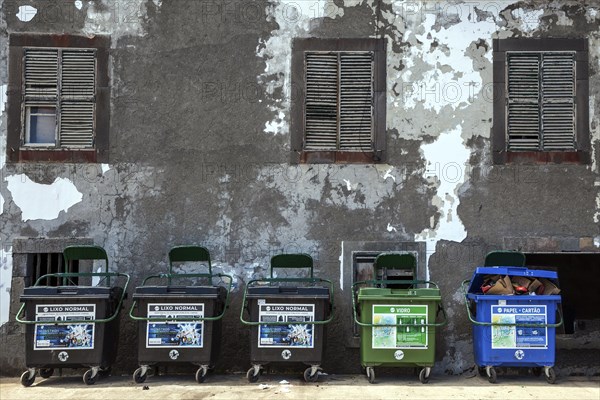 Dustbin in front of an old house wall