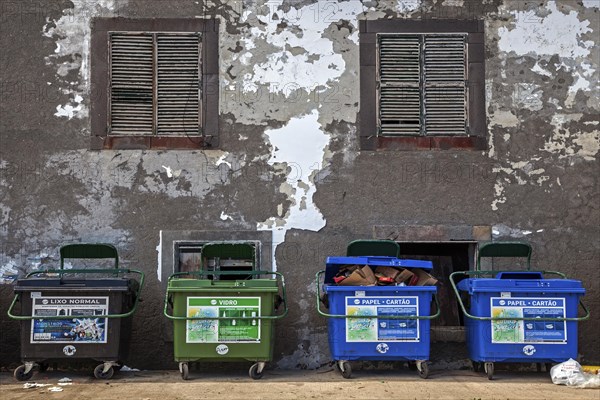 Dustbin in front of an old house wall