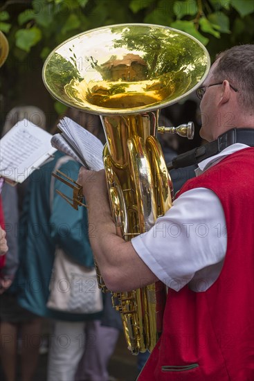 Musician holds his tuba and sheet of music ready to play