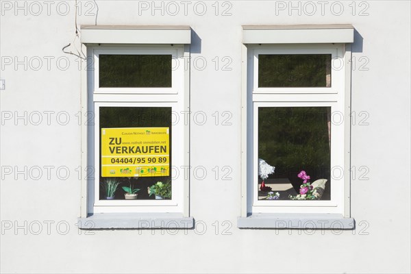 Window on an old house with sign for sale