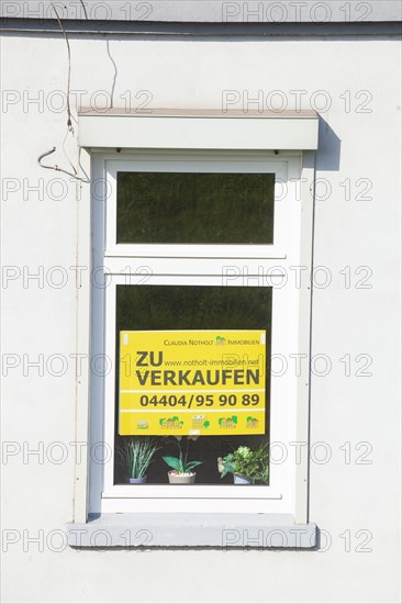 Window on an old house with sign for sale