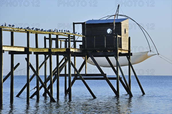 Traditional carrelet fishing hut with lift net on the beach at sunset