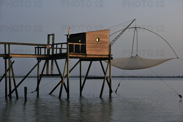 Traditional carrelet fishing hut with lift net on the beach at dusk
