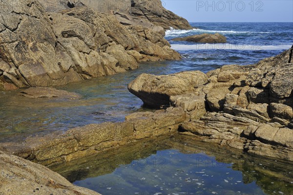 Old fish trap between the granite rocks on the shore at Saint-Guenole