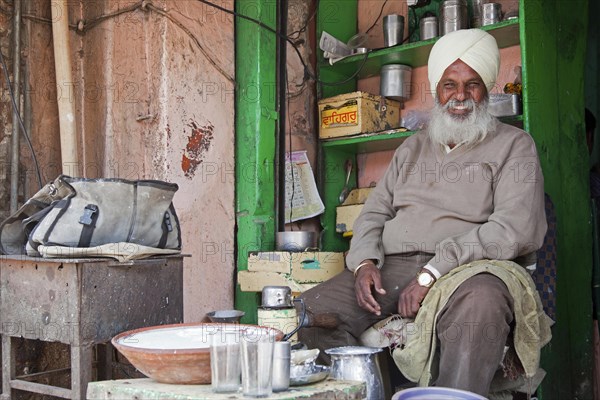 Sikh shopkeeper wearing turban selling lassi