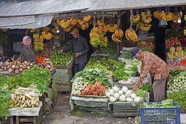 Indonesian vendor selling fruit and vegetables on display in front of grocery shop
